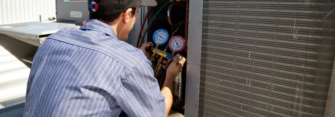 HVAC technician servicing a condenser unit in Somerdale